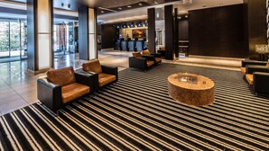 En moderne lobby med en stor lysekrone, siddeområde og en receptionsdisk.