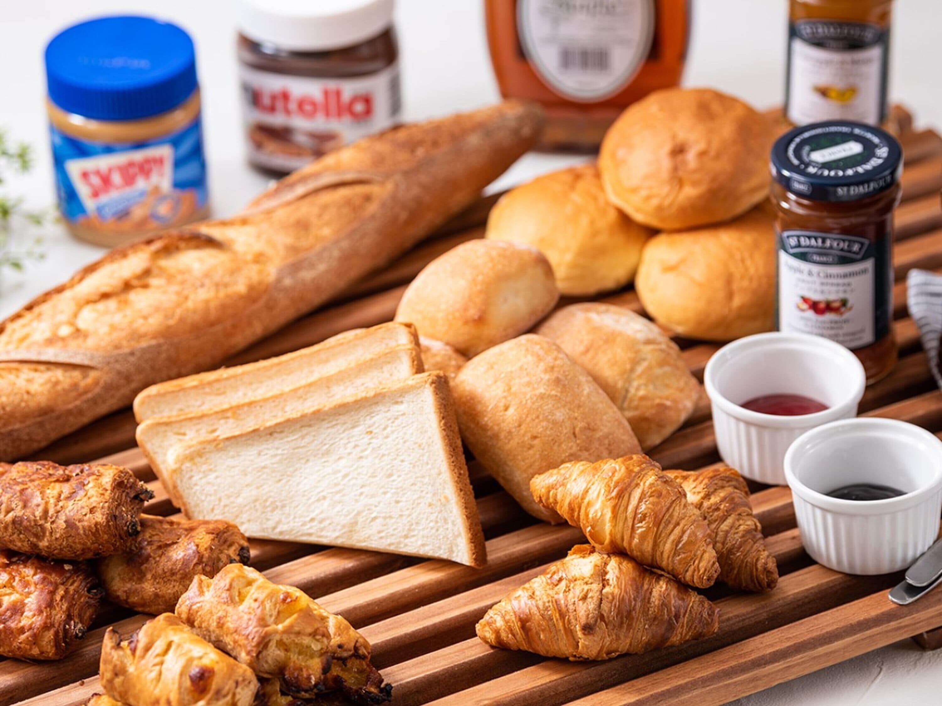 A variety of baked goods including bread, croissants, and pastries on a wooden board.