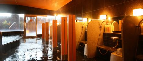 Suelo mojado en un baño público con múltiples duchas y un ventanal visible.