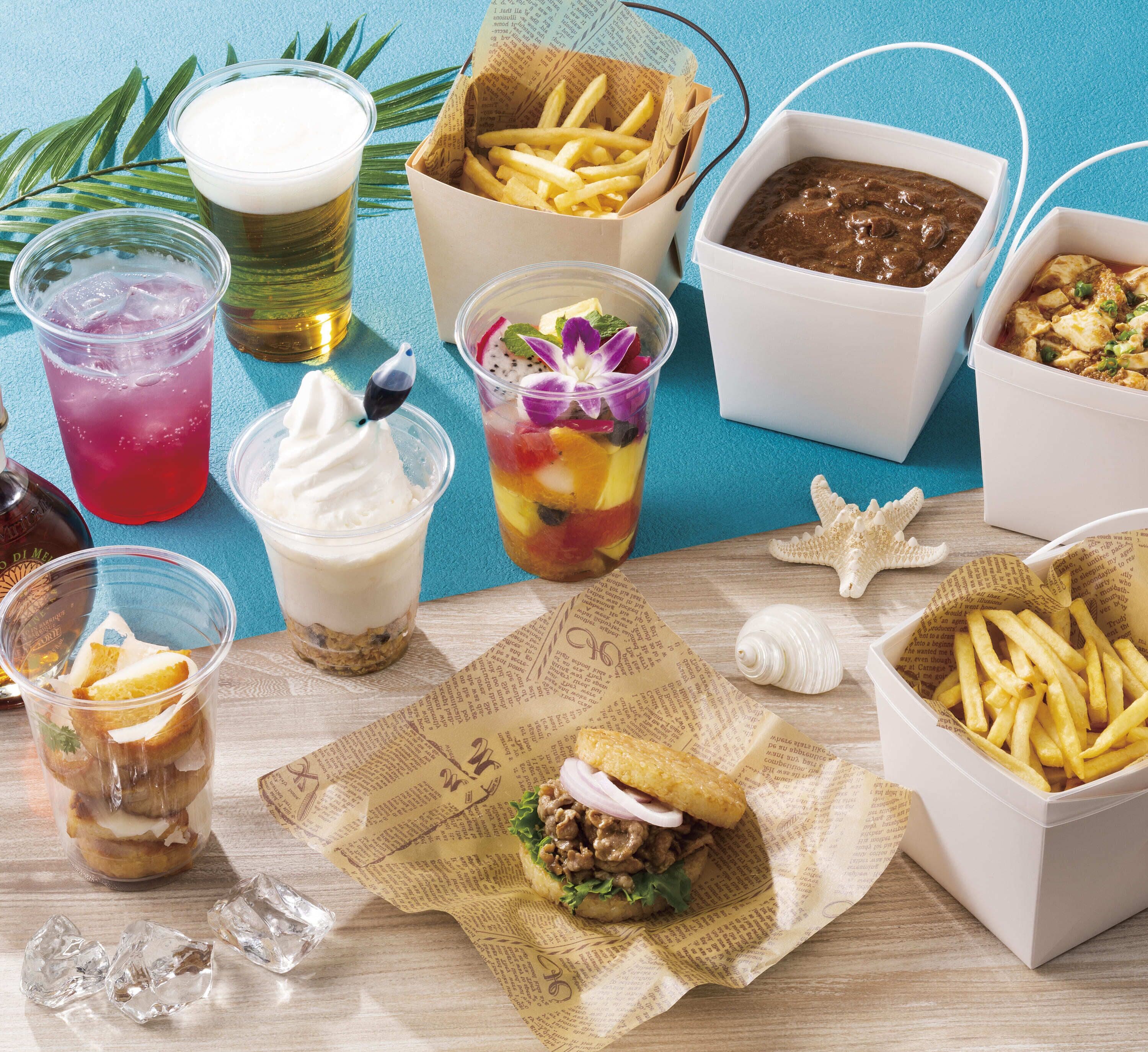 A variety of food items including a burger, fries, a drink, and a dessert on a wooden table with newspaper paper.