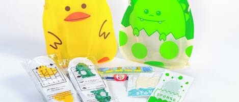Two plush toys, one yellow and one green, with accompanying packaged items.