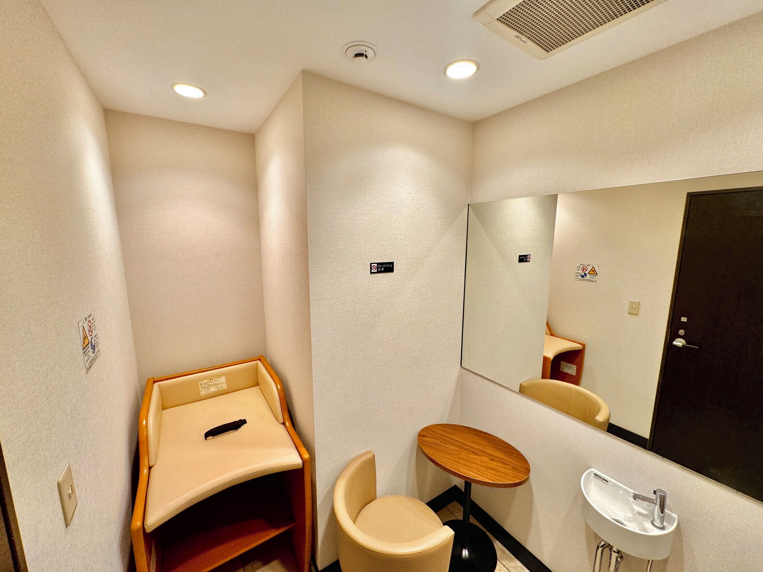 Une petite salle de bain privative comprenant des toilettes, un lavabo, un miroir et une petite table avec une chaise.