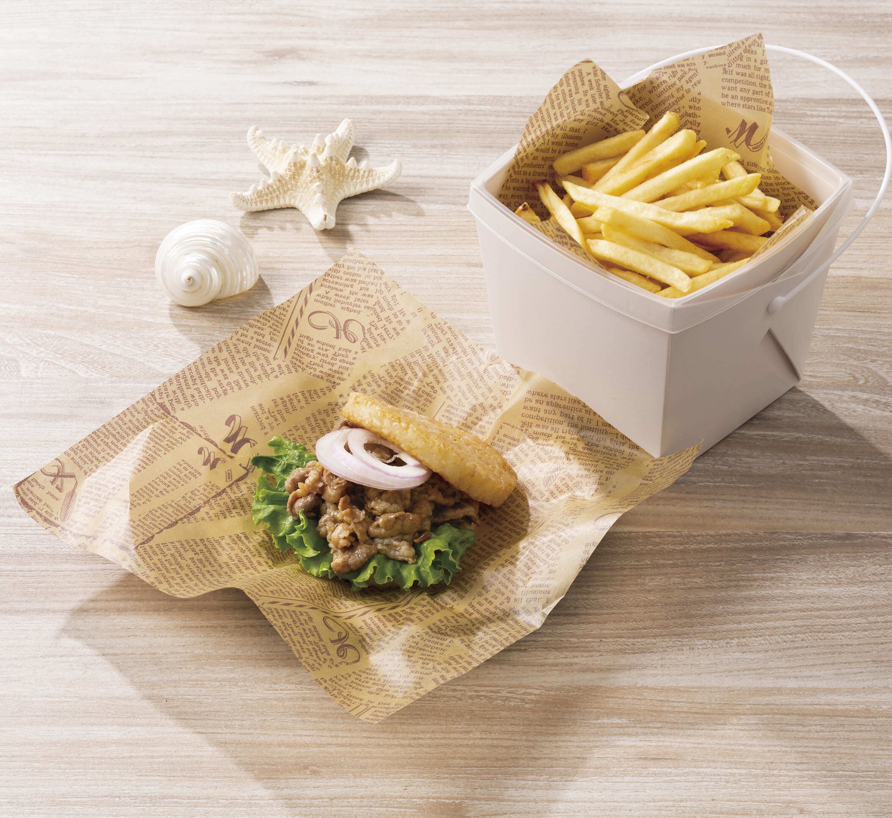 Een sandwich op een papiertje, een bakje friet en een zeester op een houten ondergrond.