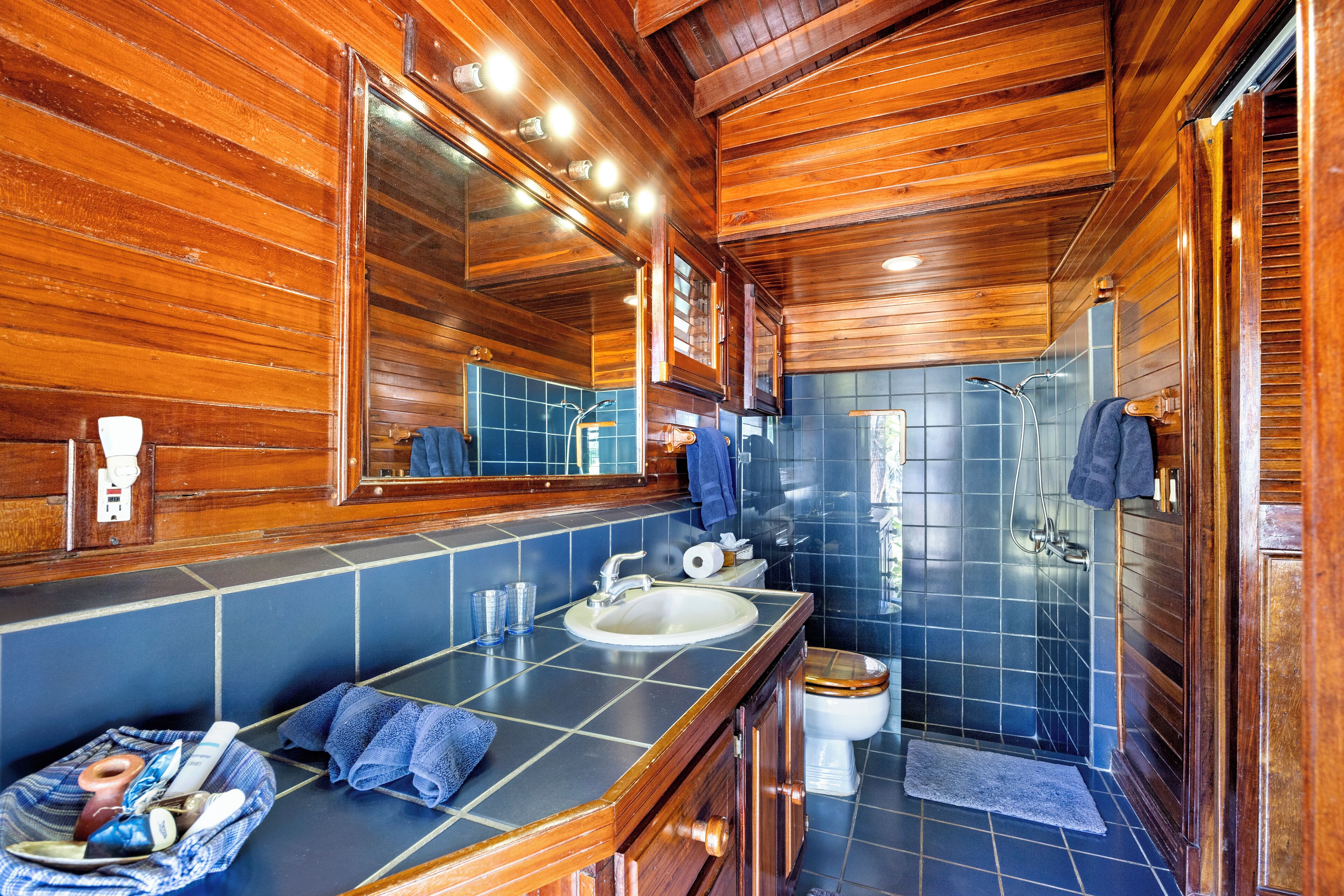 Un baño de cabaña de madera con lavamanos, espejo y ducha.