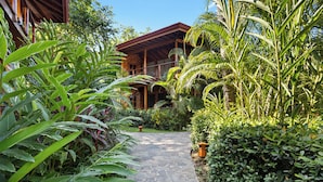Un sendero de piedra conduce a una casa de madera rodeada de exuberante vegetación tropical.