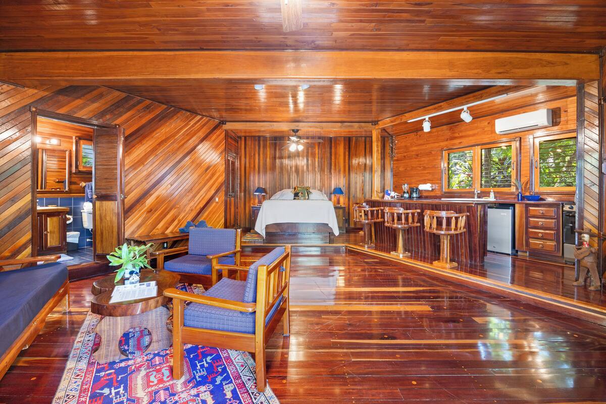 A wooden interior with a bed, seating area, and kitchen.