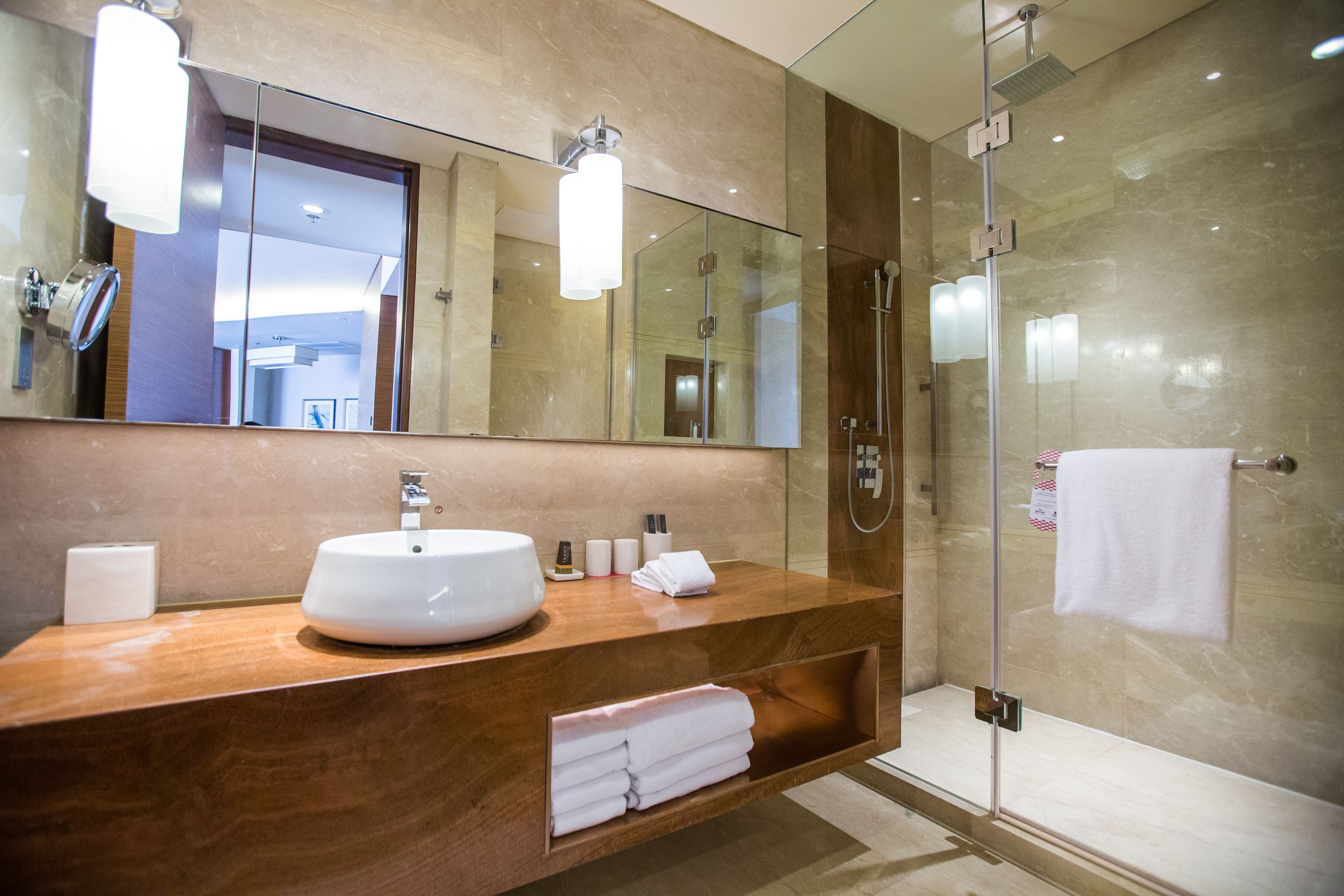 A modern bathroom with a large mirror, a sink, and a glass shower enclosure.