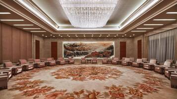A conference room with a large floral carpet, a chandelier, and a painting on the wall.