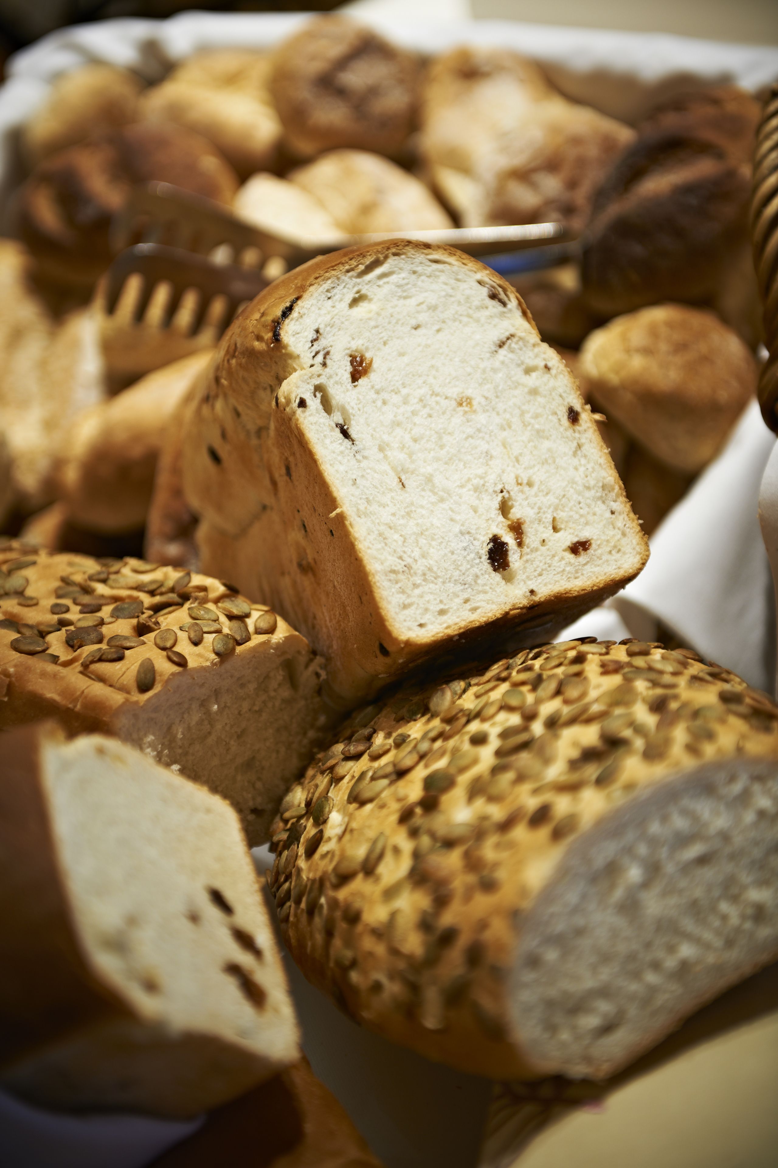 Variedad de panes, incluyendo un pan con semillas visibles y un pan rebanado con un patrón de semillas.