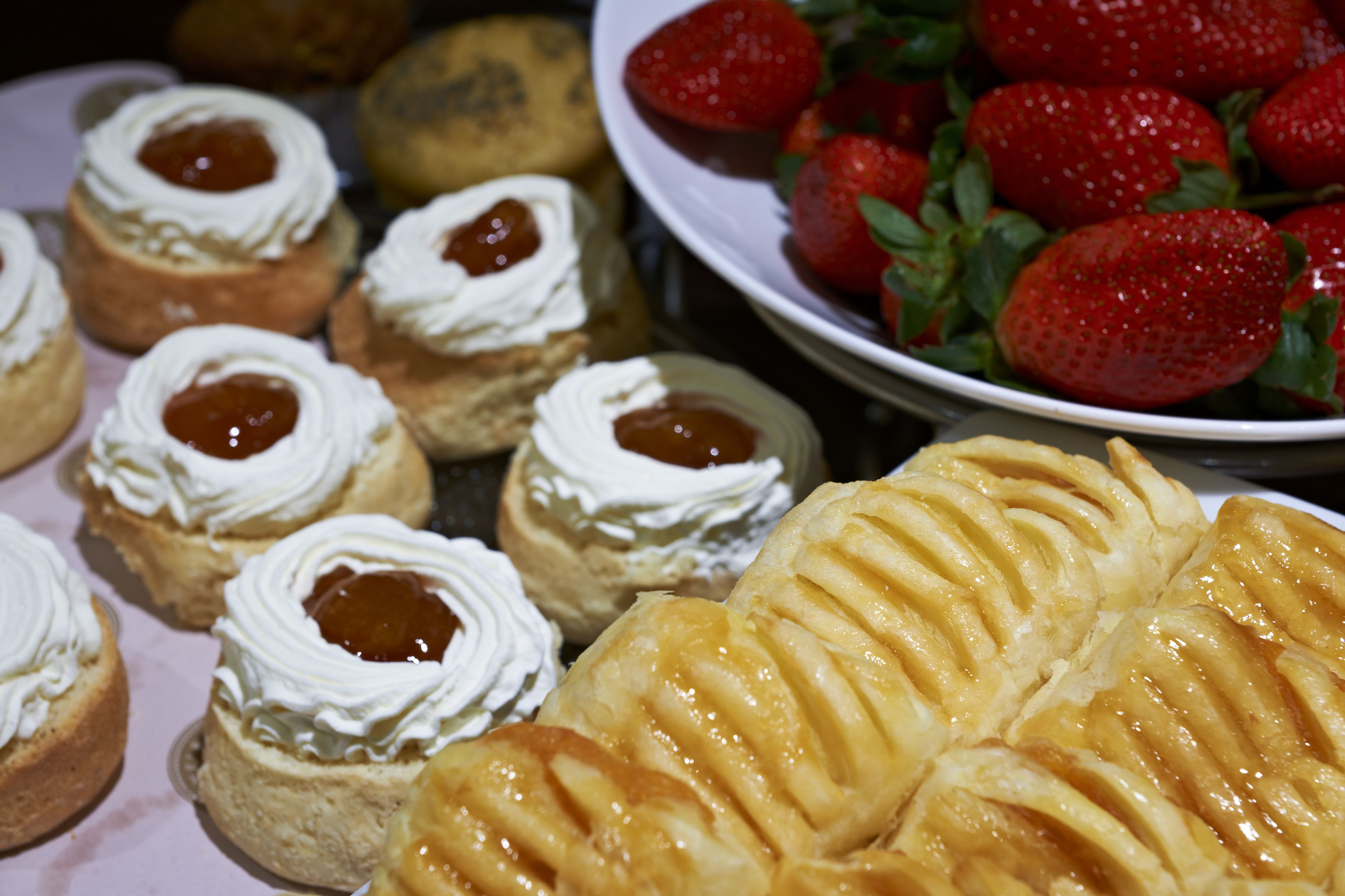 A variety of pastries including mini cakes with cream and jam, and a large apple tart.