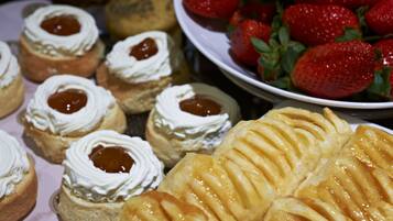 Variedad de pasteles, incluyendo mini pasteles con crema y mermelada, y un pastel grande de manzana.
