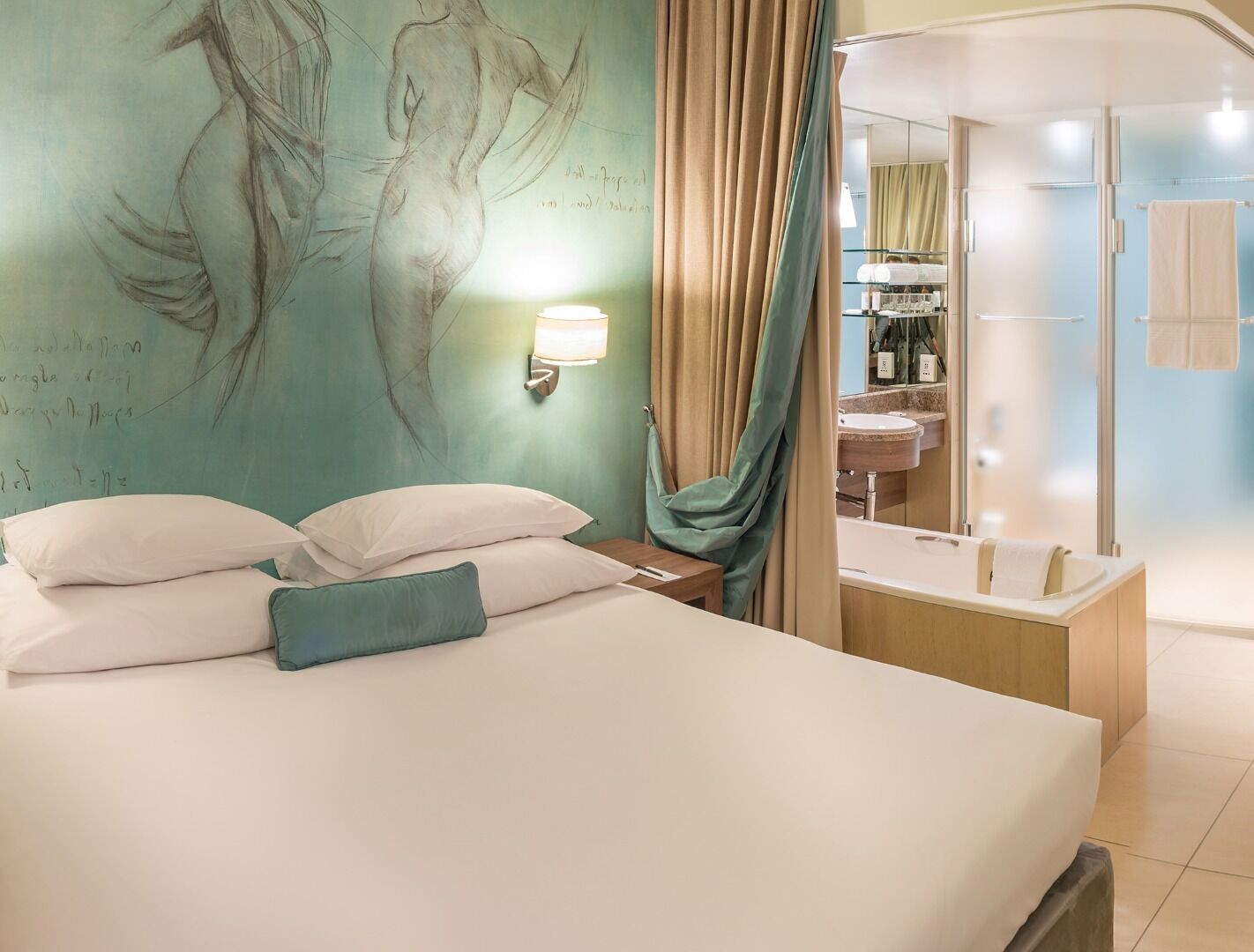 Quarto de hotel com cama, parede com mural, banheiro com banheira e chuveiro.