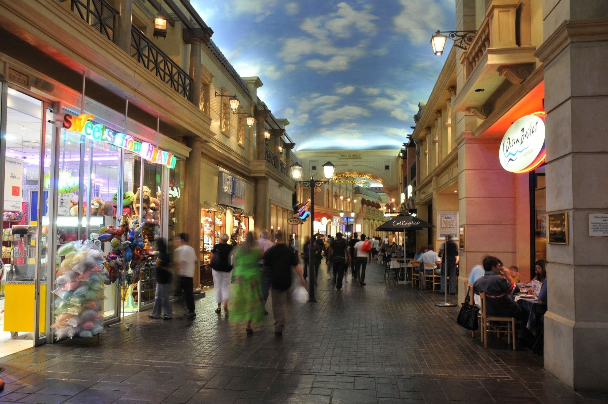 Un espacio comercial interior animado con diversas tiendas y restaurantes.