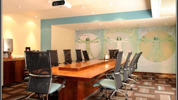 Une salle de conférence équipée d’une longue table en bois, de six chaises et d’un projecteur.