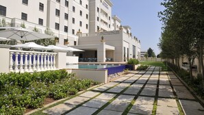 Un hotel con piscina, mobiliario exterior y un jardín bien cuidado.