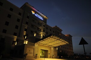 Un hotel con un letrero llamativo, un acceso cubierto y varios pisos.