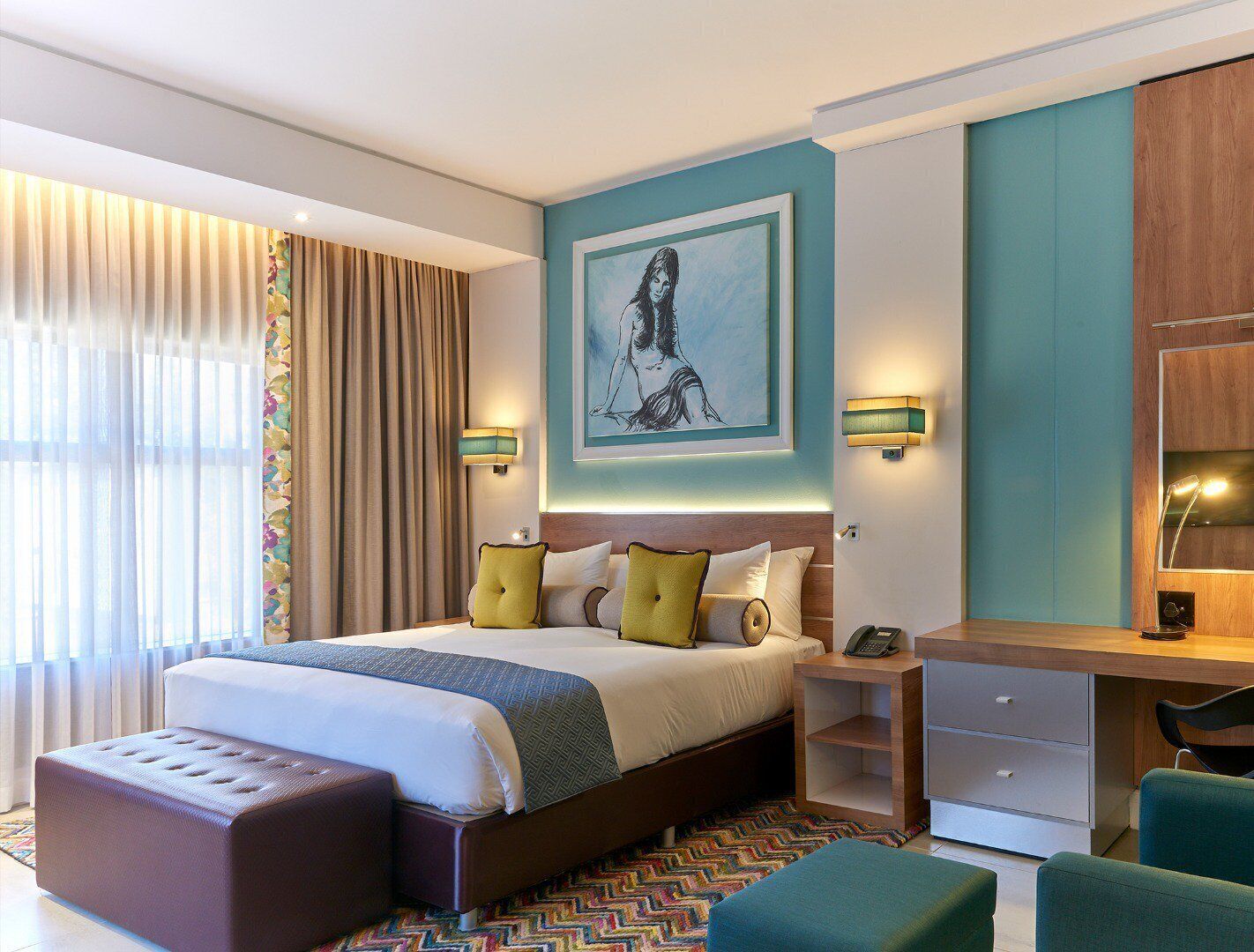Habitación de hotel moderna con una cama grande, un escritorio y una silla. Hay un cuadro en la pared y una ventana con cortinas.