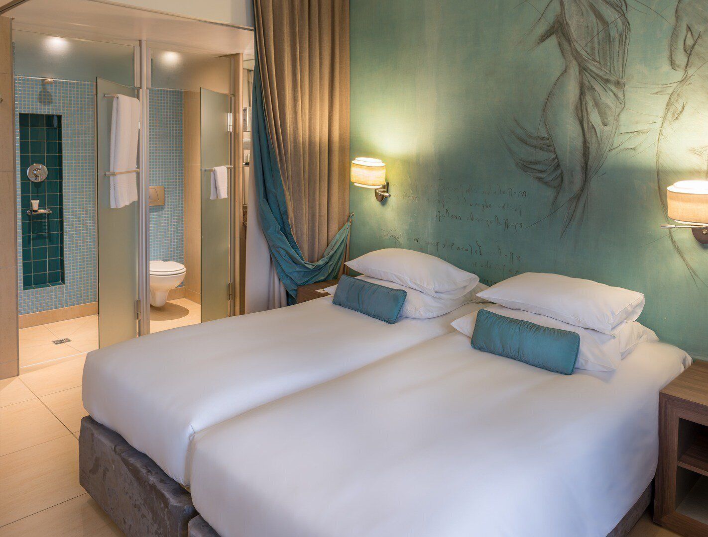 Een hotelkamer met een bed, twee wandlampen, een douche en een muurschildering.