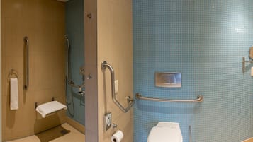Une salle de bain équipée d’une douche, de toilettes et de barres d’appui.