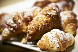 Una bandeja con varios pasteles, incluyendo cruasanes y un pastelito espolvoreado con azúcar glas.