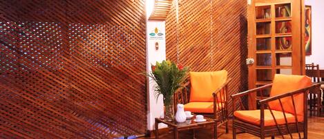 A room with a wooden floor, a bamboo partition, and a table with a vase of flowers.