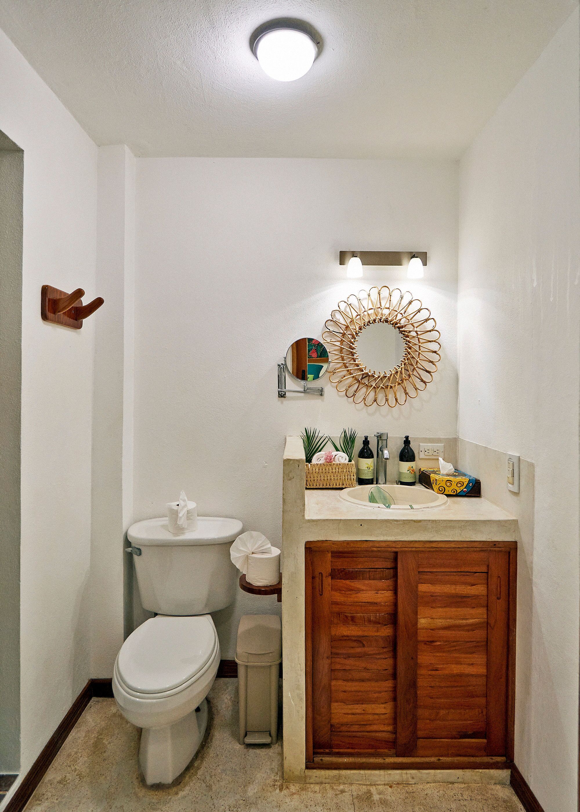 A bathroom with a toilet, sink, and mirror.
