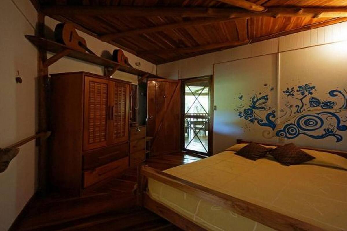 Un dormitorio con una cama de madera, un armario y un detalle decorativo en la pared.