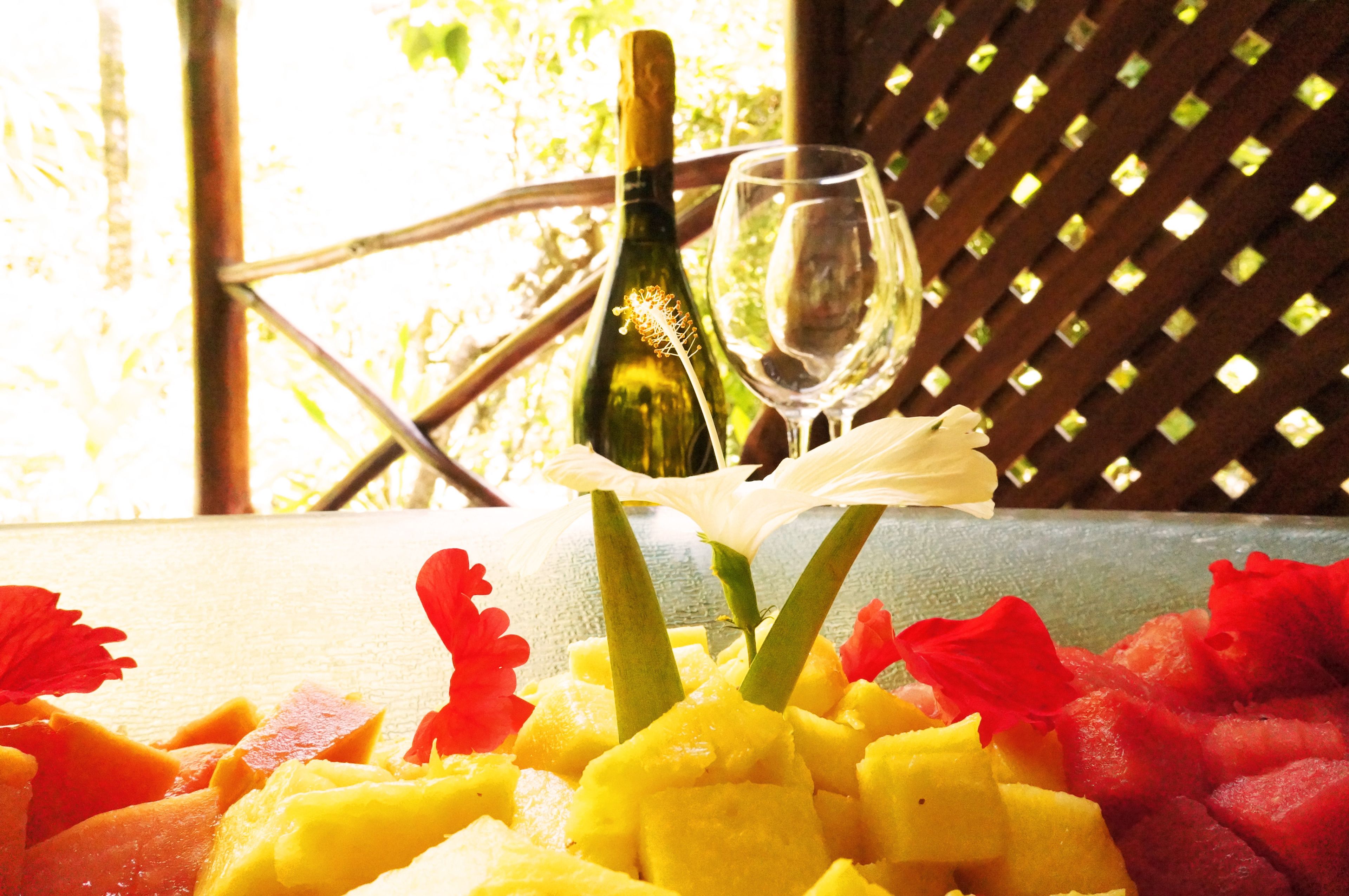 Una mesa con una botella de vino, una copa de vino y una disposición de frutas.