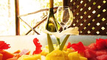 Una mesa con una botella de vino, una copa de vino y una disposición de frutas.