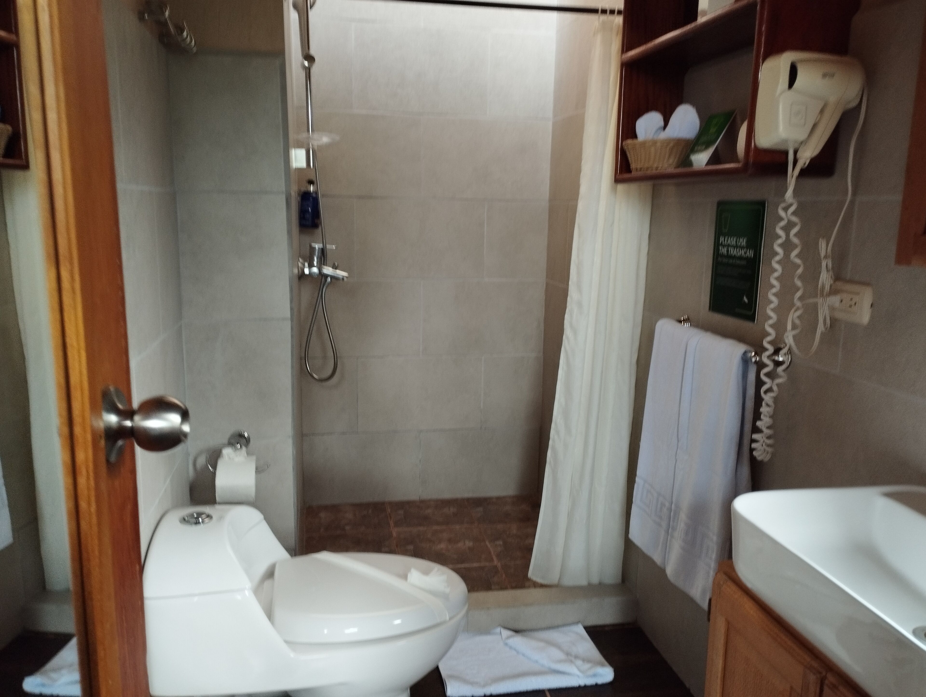 Uma casa de banho com sanita, chuveiro e lavatório.