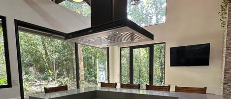 Una cocina moderna con una isla central, ventanas amplias y un ventilador de techo.