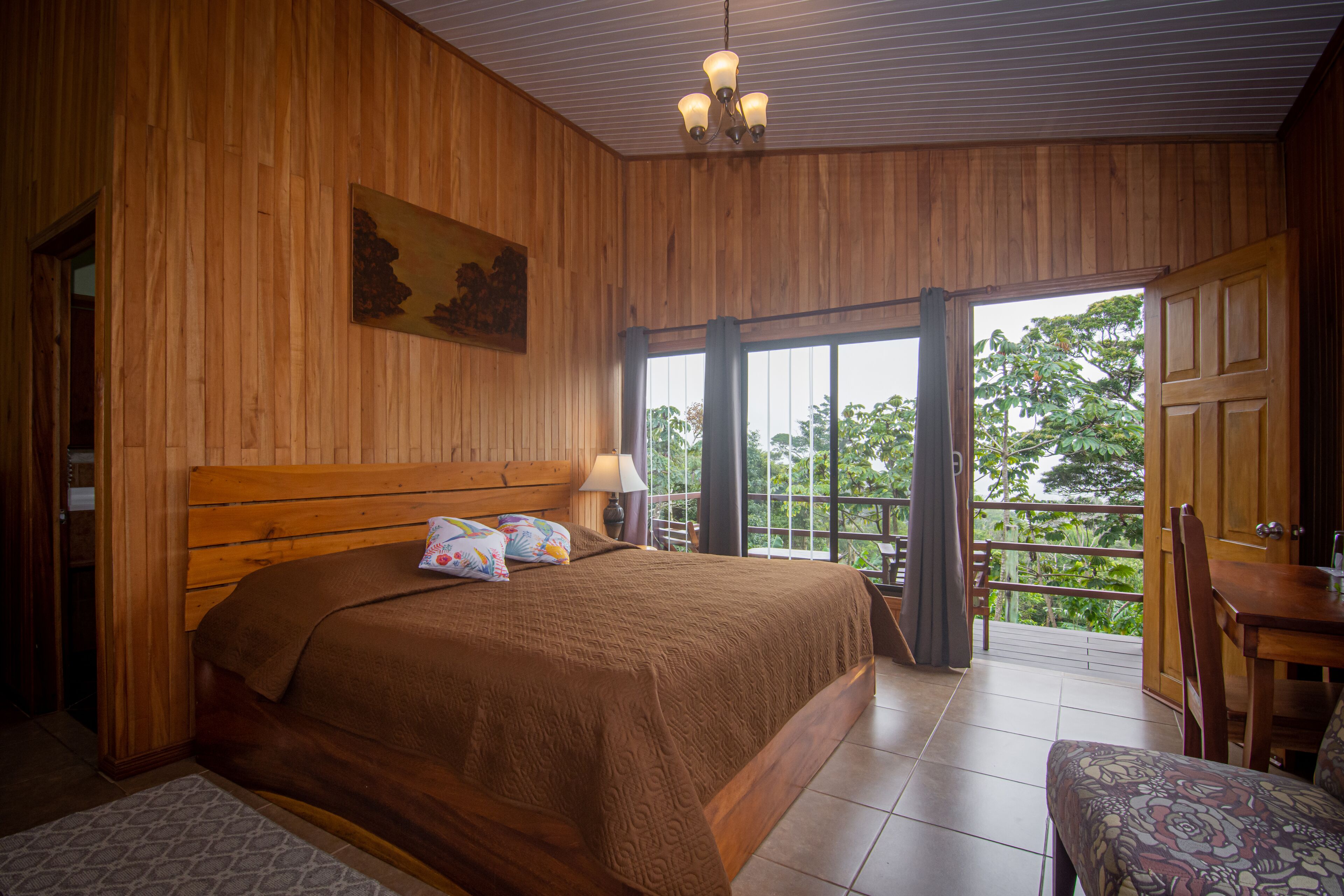 Quarto de madeira com uma cama, uma mesa e uma cadeira.