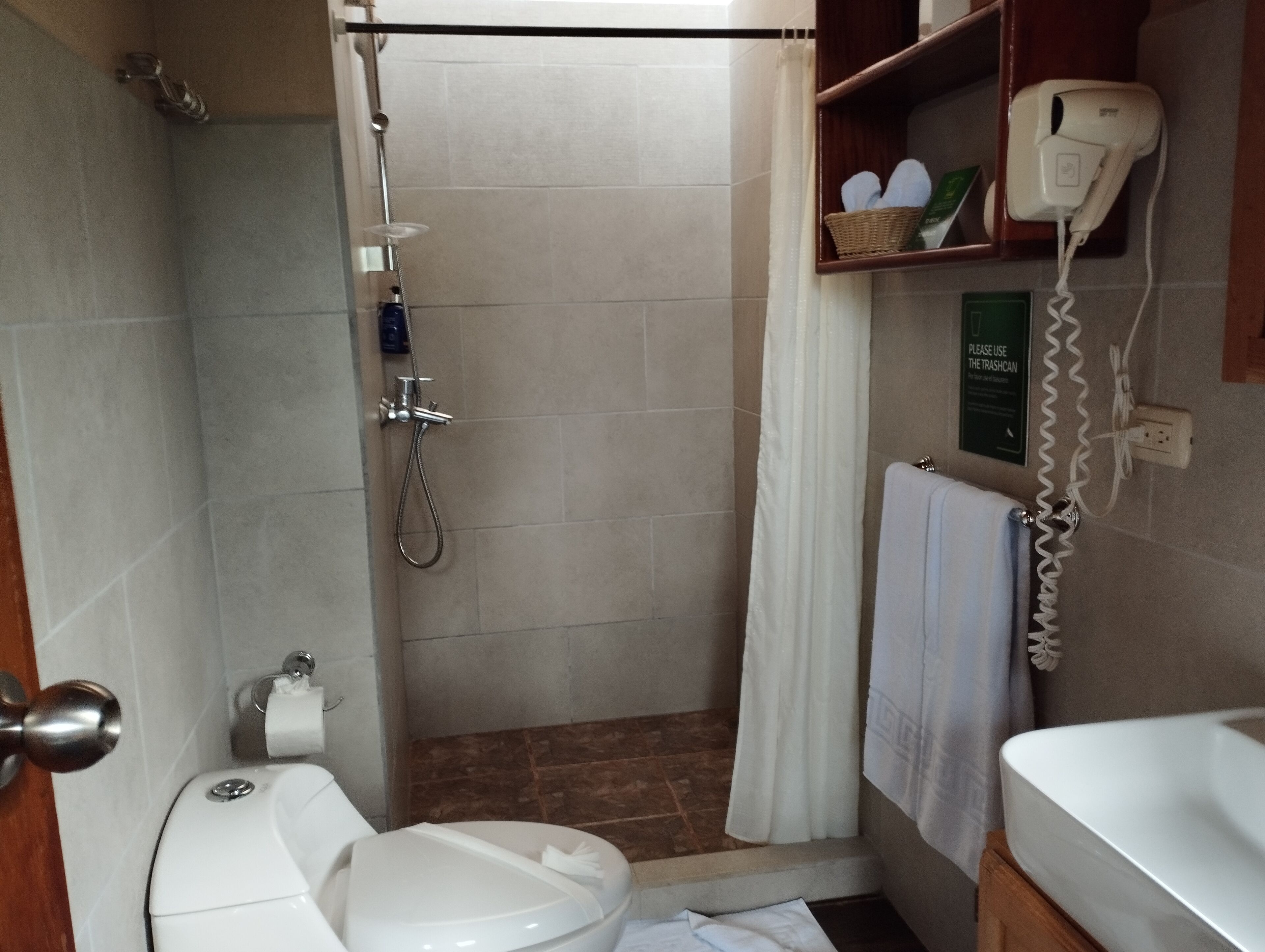 A bathroom with a shower, toilet, and a towel rack.