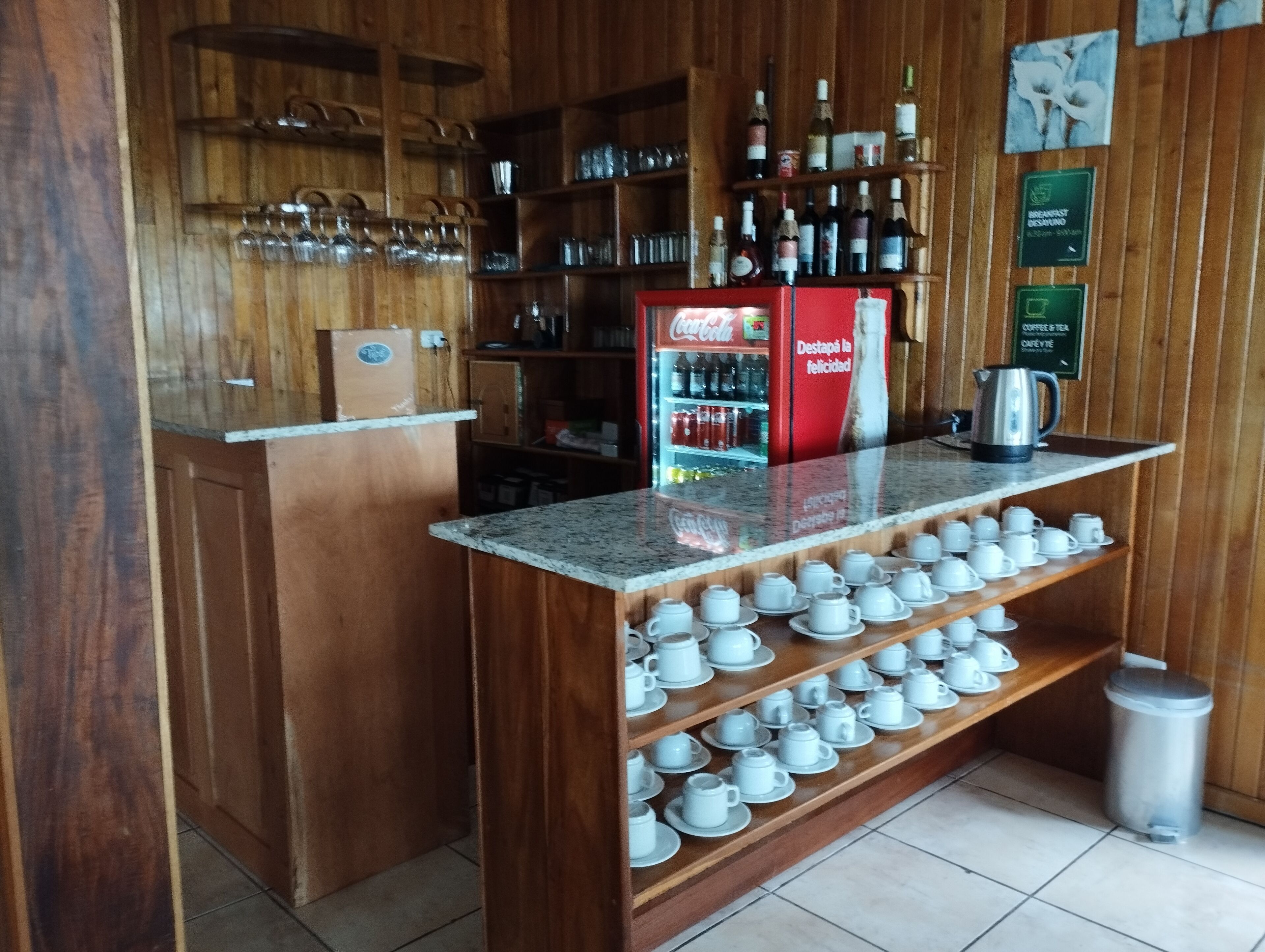 A bar area with shelves of bottles, a Coca-Cola refrigerator, and a coffee station.