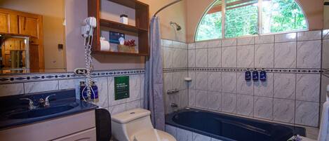 A bathroom with a toilet, sink, and bathtub. There is a shower curtain, a towel rack, and a window with a view of trees.
