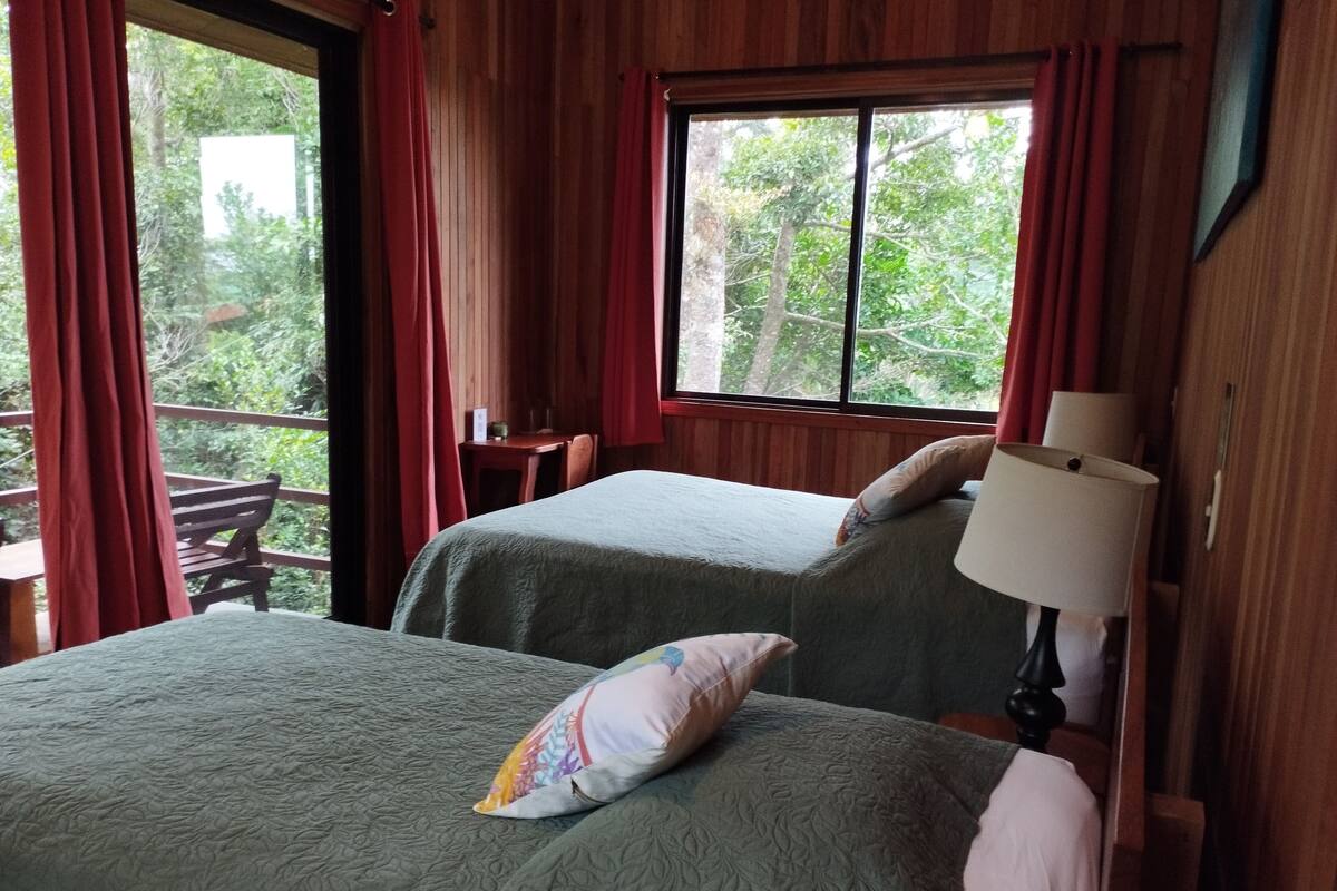 A room with two beds, a table, and a chair.