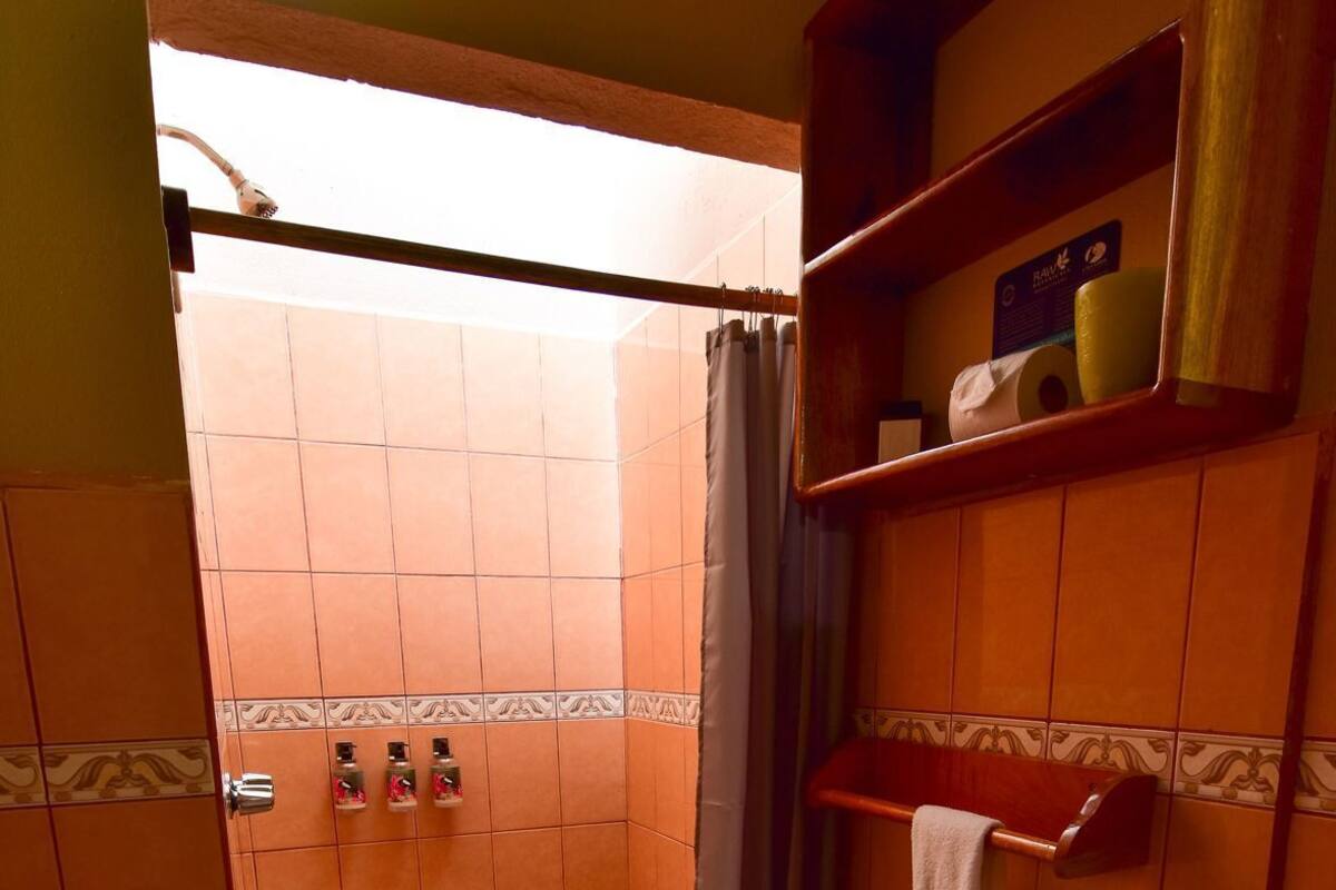 A bathroom with a toilet, shower, and shelves with toiletries.