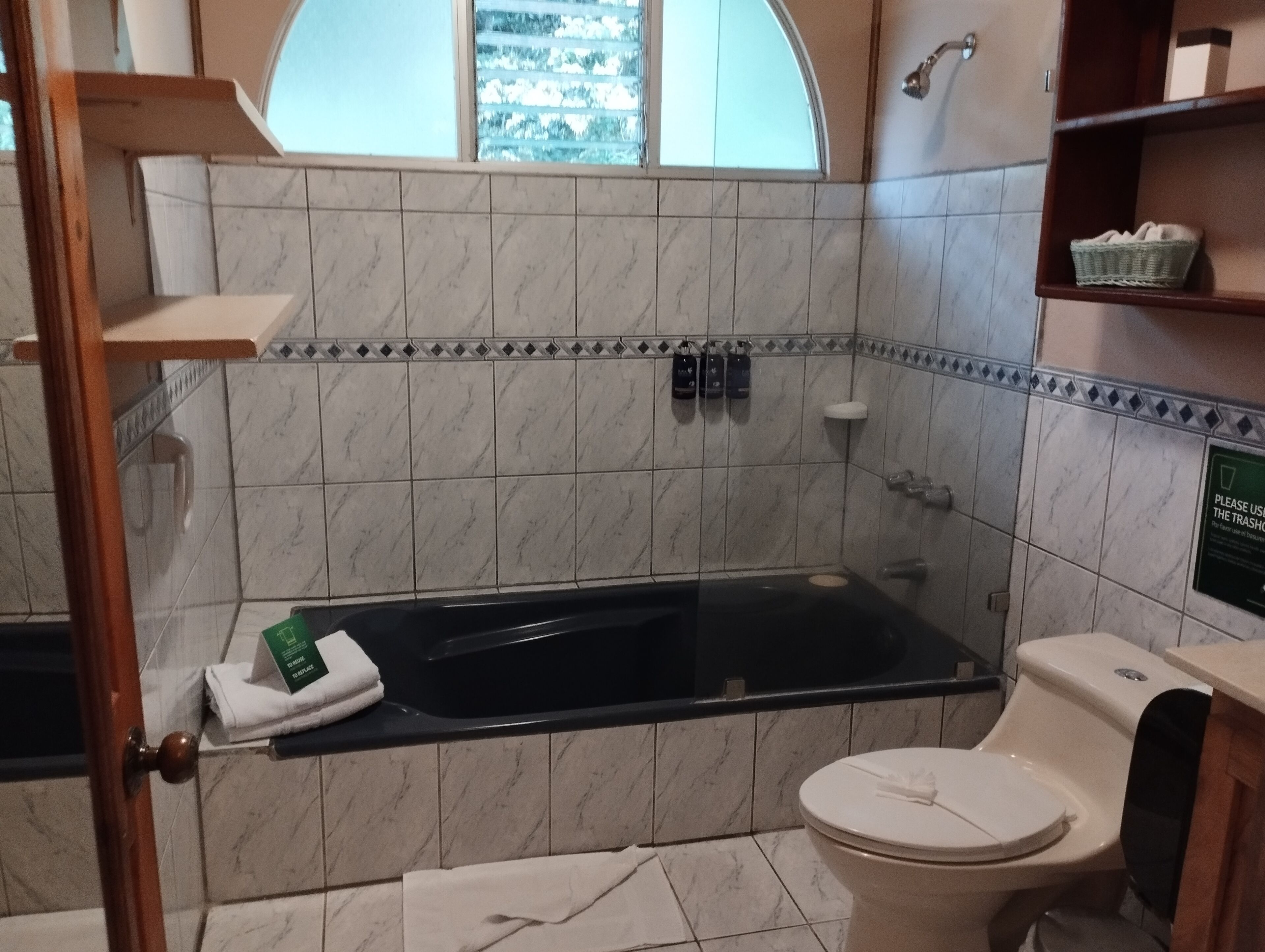 Casa de banho com banheira, sanita e estantes com artigos de higiene pessoal.