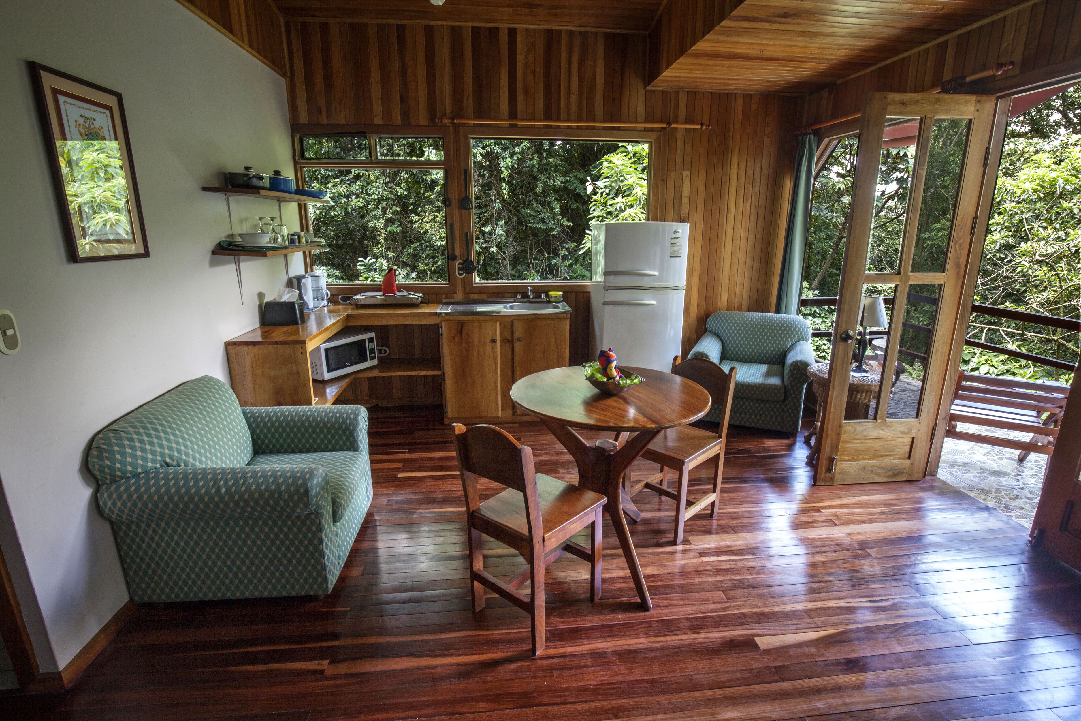Une cuisine de taille réduite, dotée de meubles en bois, d’un réfrigérateur et d’un coin repas avec une table et des chaises.