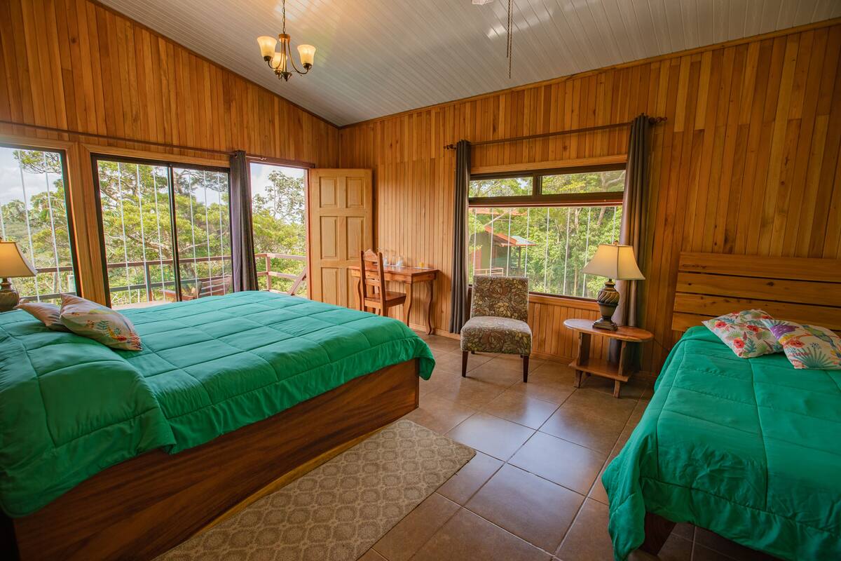 A wooden room with two beds, a desk, and a chair.