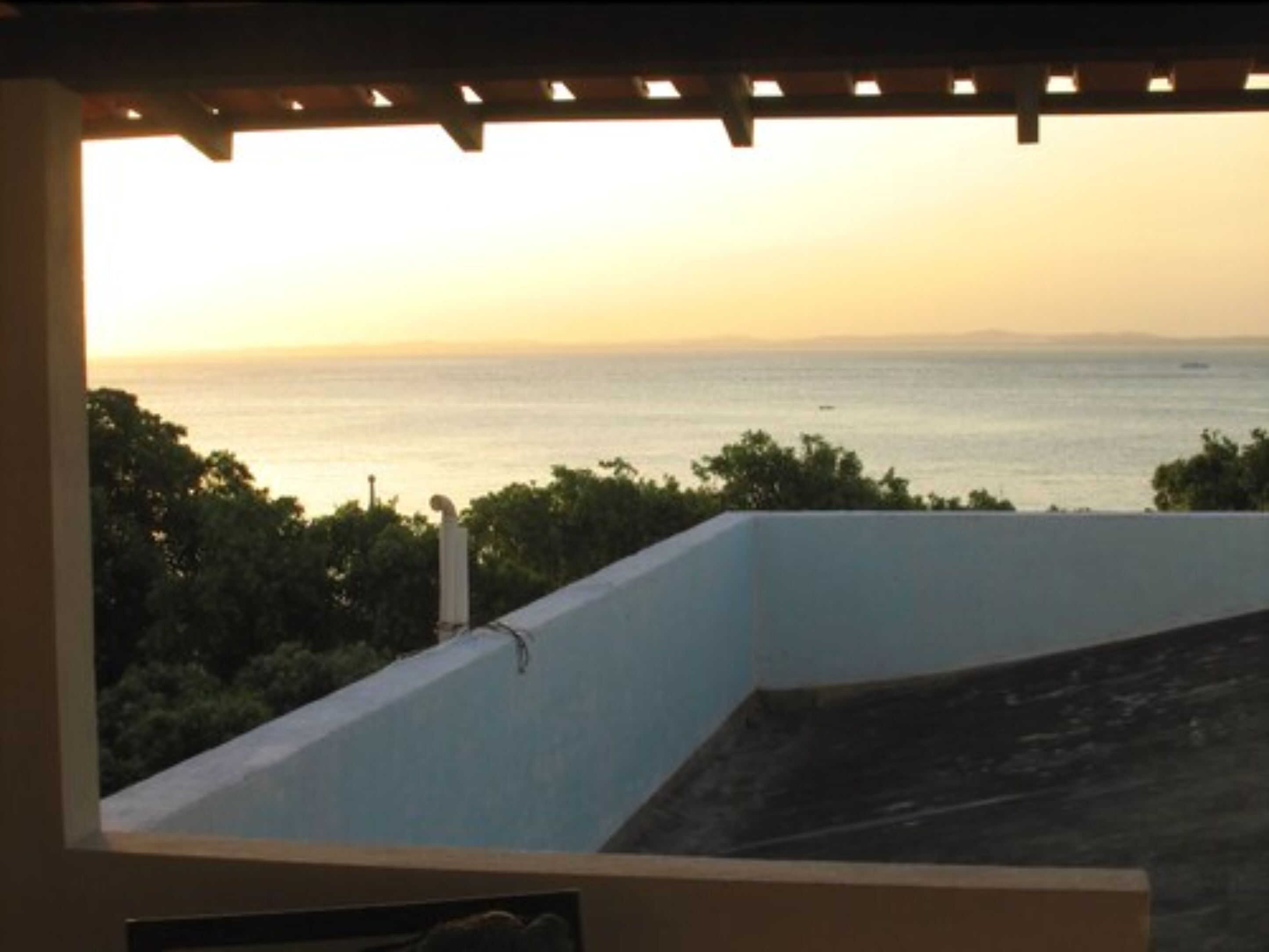 A balcony with a view of the sea during sunset.
