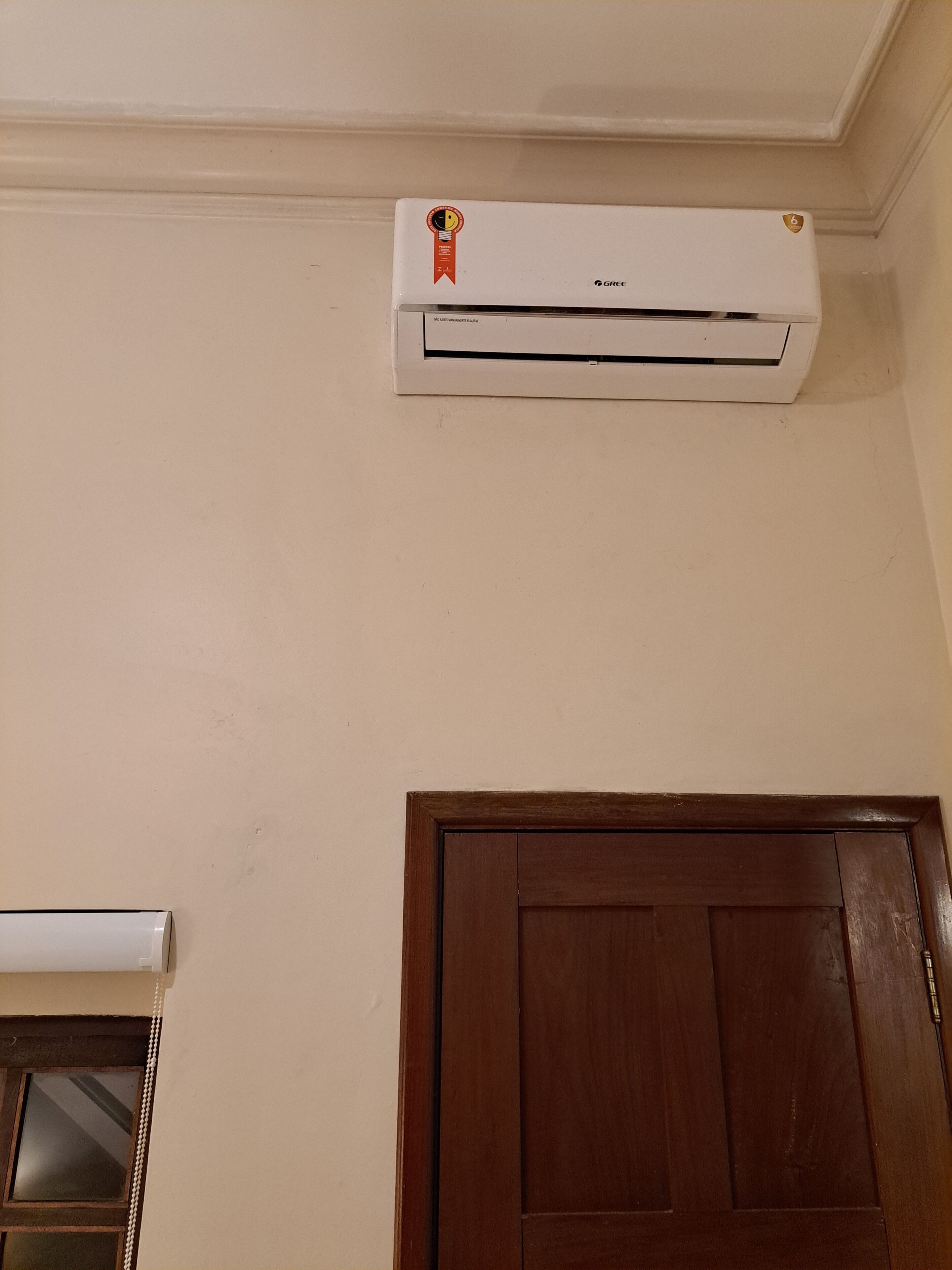 A white air conditioning unit mounted on a wall with a wooden door below it.