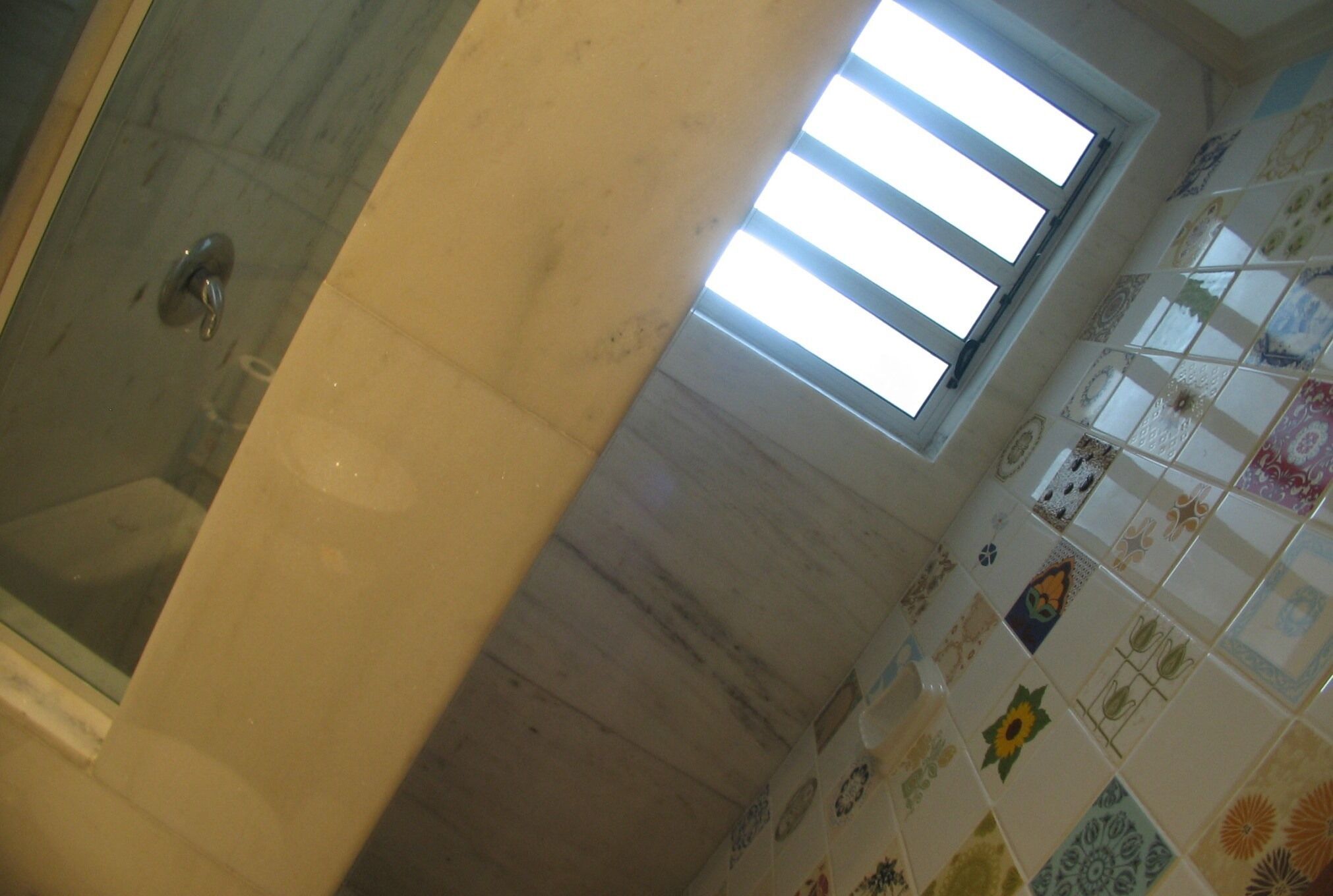 A bathroom with a shower, a window, and tiled walls.
