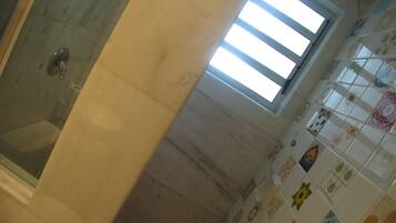 A bathroom with a shower, a window, and tiled walls.