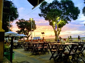 Enjoy dining under the stars in this serene outdoor setting, surrounded by lush trees and comfortable seating.