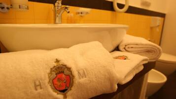 A bathroom with a sink, a towel with a crest, and a toilet.