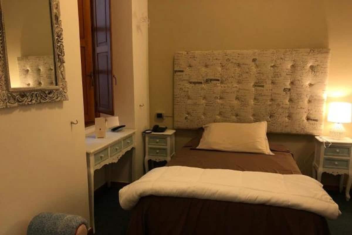 A bedroom with a bed, a dresser, a mirror, and a nightstand.