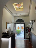 Un hall de hotel con una recepción, una puerta de cristal y un techo decorativo.