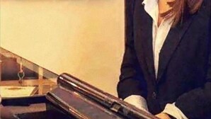 A person sitting at a desk with a wooden key rack in the background. - Hotel Medici (Milazzo)