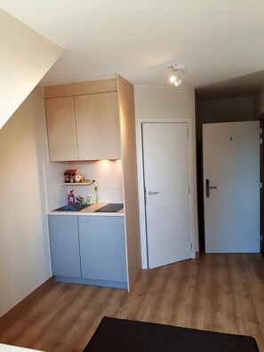 A compact kitchen with a built-in cabinet, a white door, and a wooden floor.